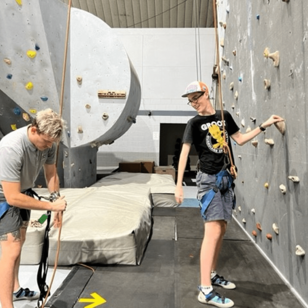 Participant on an indoor climbing wall with a support worker