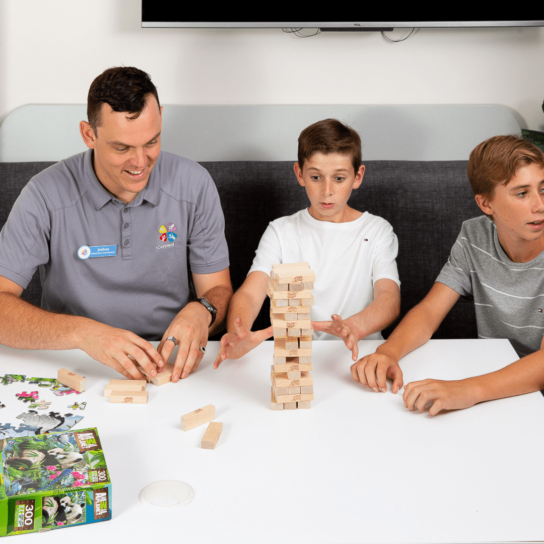 iConnect Life support worker playing a block-stacking game with two boys
